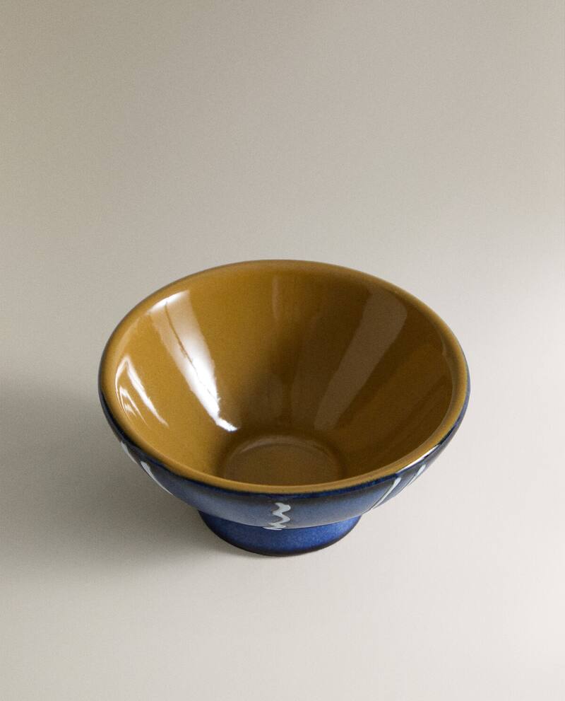 Medium shot of the top of a blue creamic bowl with white stripes