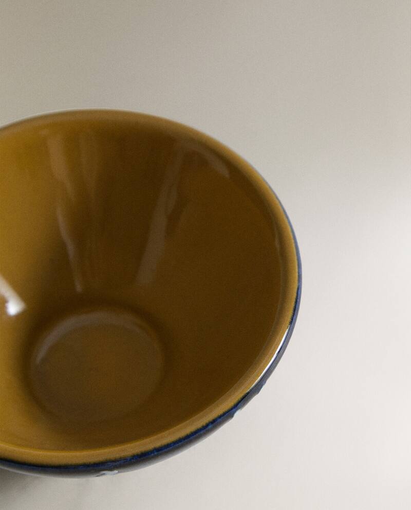 Closeup of the top of a blue ceramic bowl with white stripes