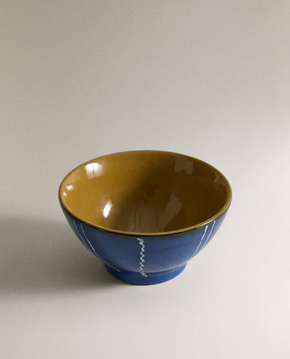 Medium shot of the top of a blue creamic bowl with white stripes