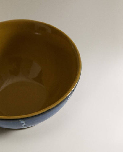 Closeup of the top of a blue ceramic bowl with white stripes