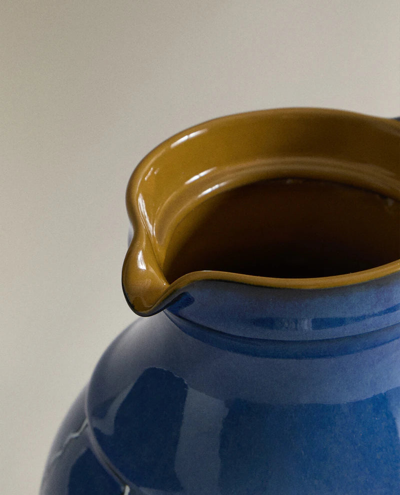 Closeup of the top of a blue ceramic vase with white stripes