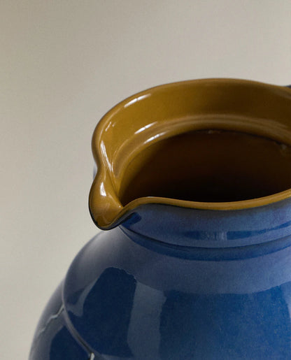 Closeup of the top of a blue ceramic vase with white stripes