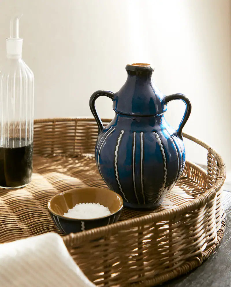 Blue ceramic vase with blue stripes on a rattan tray